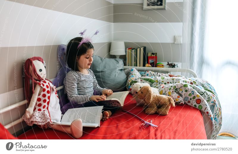 Kleines Mädchen sitzt auf dem Bett und liest ihrem Spielzeug ein Buch vor Freude schön Spielen lesen Schlafzimmer Kind Lehrer sprechen Mensch Frau Erwachsene