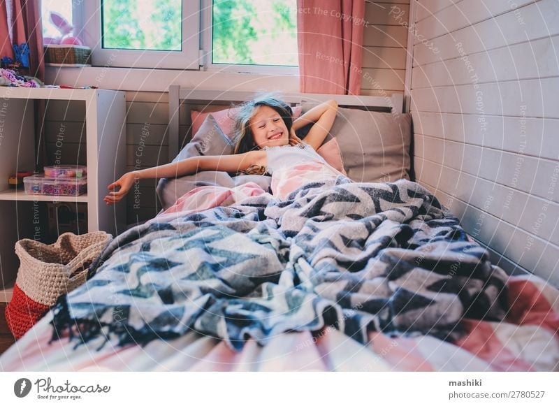 glückliches Kind Mädchen Aufwachen am frühen Morgen in ihrem Zimmer, im Bett liegend Lifestyle Glück Erholung Spielen Schlafzimmer Schulkind Kindheit lachen
