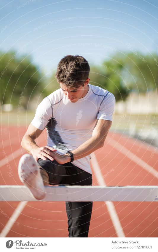Junger Sportler streckt die Beine aus Mann strecken Stadion Körperhaltung beweglich Fitness üben Athlet muskulös Gesundheitswesen Erwachsene Sprinter sportlich