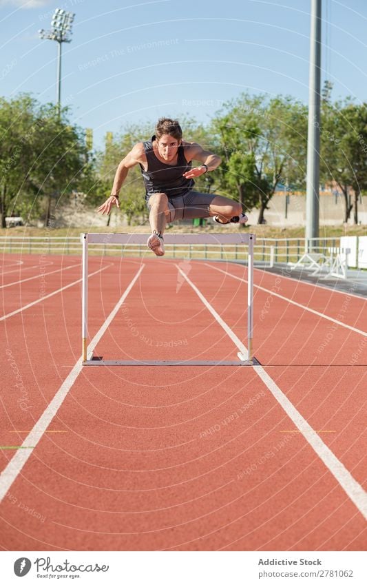 Sportler beim Springen über eine Hürde Körperhaltung Stadion stehen Fitness Athlet Rennbahn üben Schiffsplanken Mann muskulös Gesundheitswesen Erwachsene