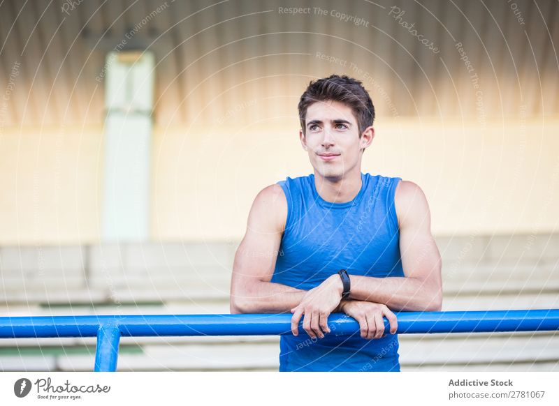 Junger Mann in Sportbekleidung, der sich auf einen Metallzaun lehnt und sich auf der Bühne posiert. Stadion sportlich Körperhaltung ruhen Sportler Fitness
