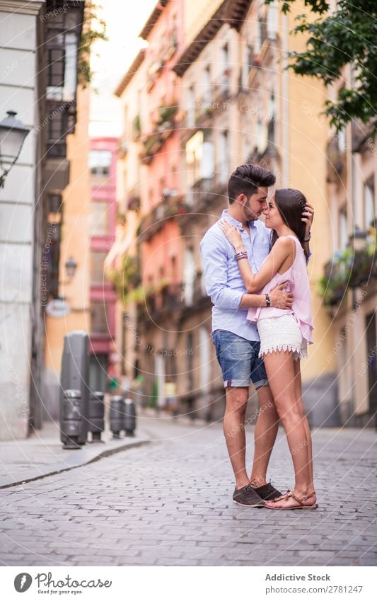 Romantisches Paar, das sich auf der Straße gegen Gebäude umarmt. Profil Küssen Zeitpunkt Romantik Angesicht zu Angesicht Fassade Hintergrundbild lässig