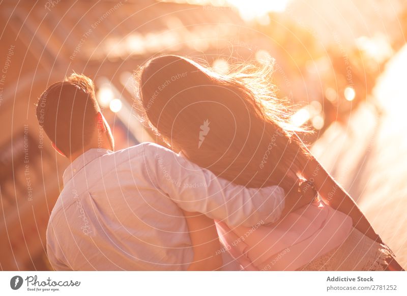 Nicht erkennbares Paar, das sich gemeinsam umarmt. Umarmen Straße Rückansicht Sonnenlicht hell unkenntlich laufen Heck Unschärfe Sonnenstrahlen brünett