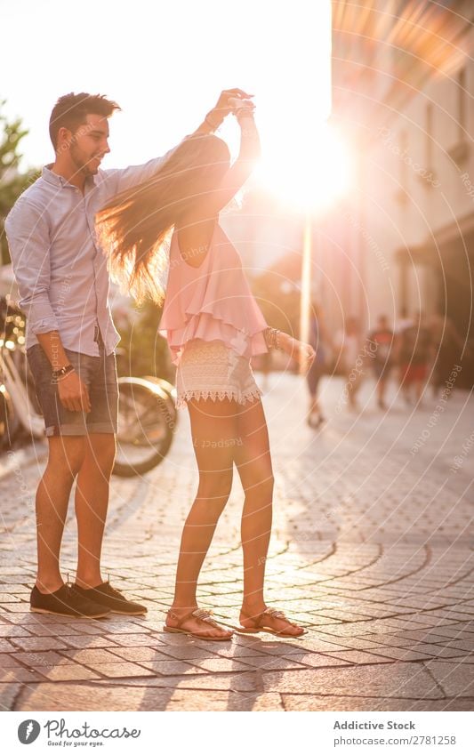 Freundin mit fliegenden Haaren, die auf der Straße tanzt und die Hand ihres Freundes hält. Paar Tanzen Romantik romantisch Sonnenlicht hell