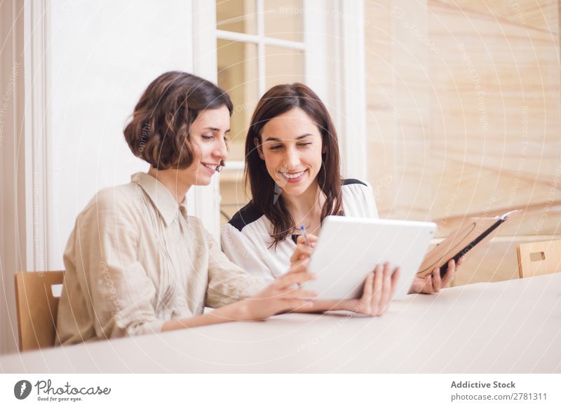 Junge Frauen, die auf das Tablett schauen und lächeln. Lächeln Tablet Computer Mitteilung Technik & Technologie heiter zeigen benutzend Business