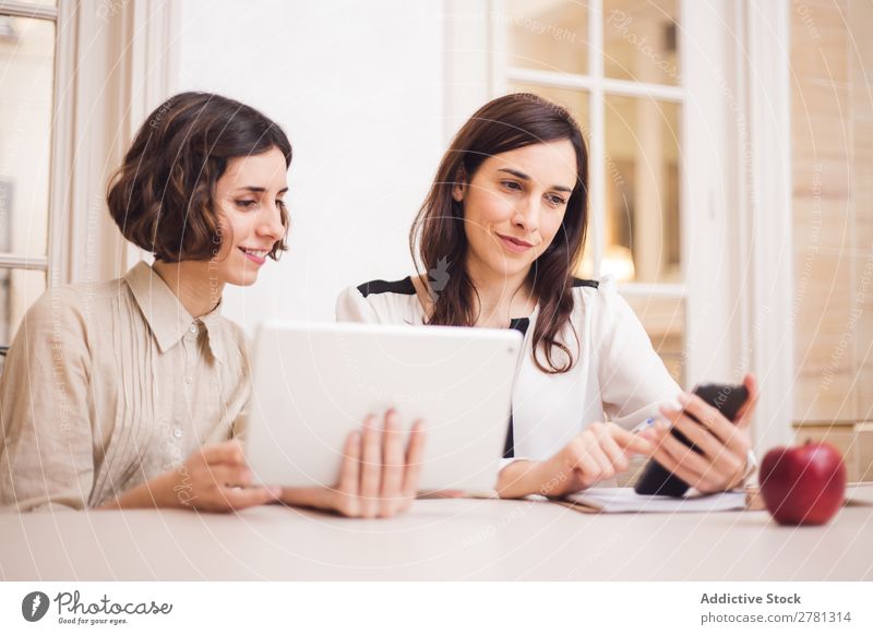 Junge Frauen, die auf das Tablett schauen und lächeln. Lächeln Tablet Computer Mitteilung Technik & Technologie heiter zeigen benutzend Business