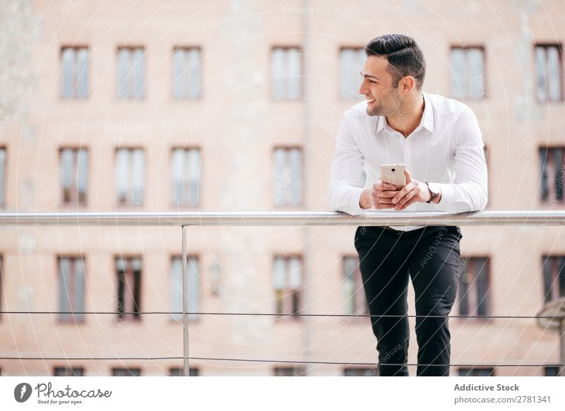 Glücklicher Geschäftsmann hält Smart Phone, während er gegen das Gebäude steht. 20s Erwachsene Architektur weg Business Geschäftsleute Kaukasier Mitteilung