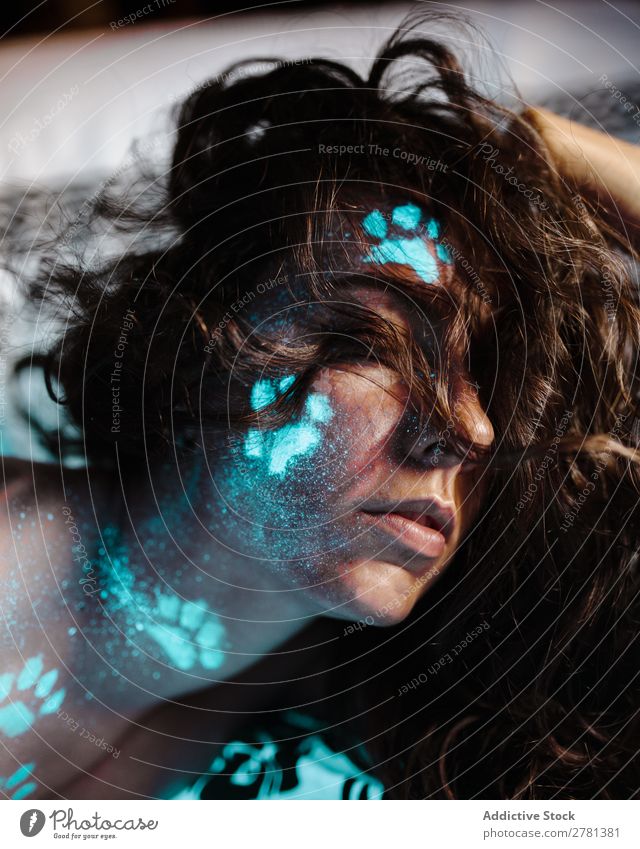 Frau mit fluoreszierenden Spuren im Gesicht Jugendliche hübsch Farbe malen Freitreppe blau Fußspur Tier leuchten erleuchten Kunst neonfarbig Licht Mode