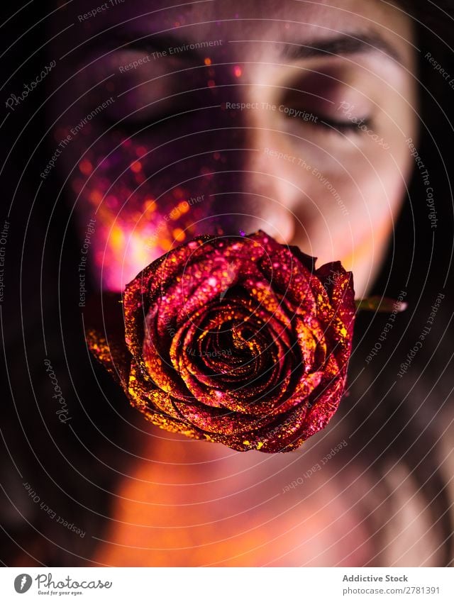 Junge Frau mit glitzernder Rose im Mund Jugendliche hübsch Augen geschlossen rot glänzend Farbe malen fluoreszierend leuchten erleuchten Kunst neonfarbig Licht