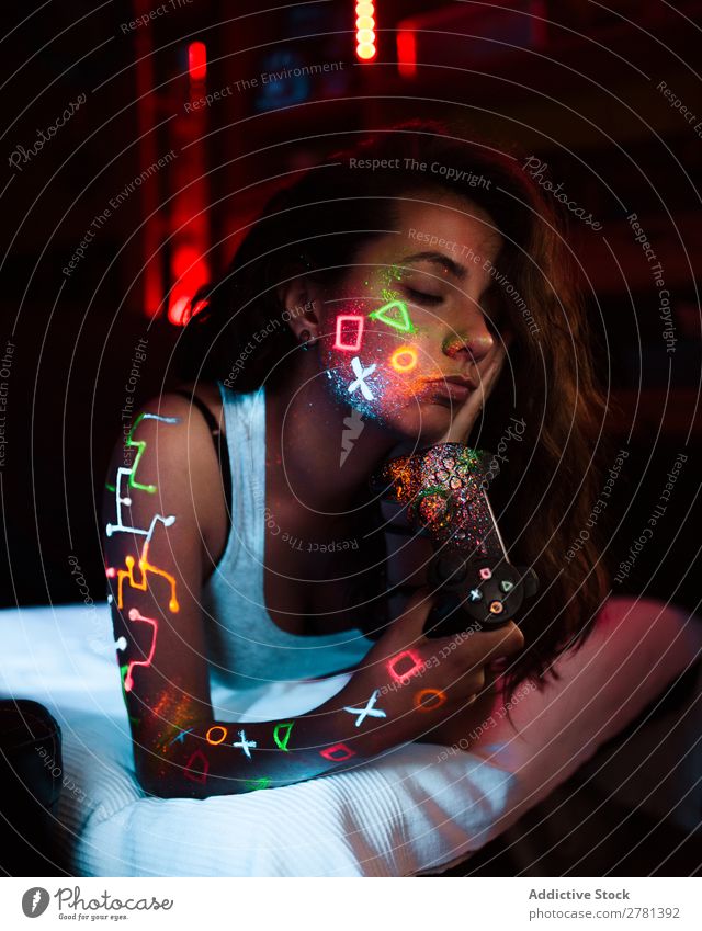 Spielerin mit fluoreszierender Farbe Frau Jugendliche hübsch Spielfeld Konsole Augen geschlossen Regler malen leuchten erleuchten Kunst neonfarbig Licht Mode