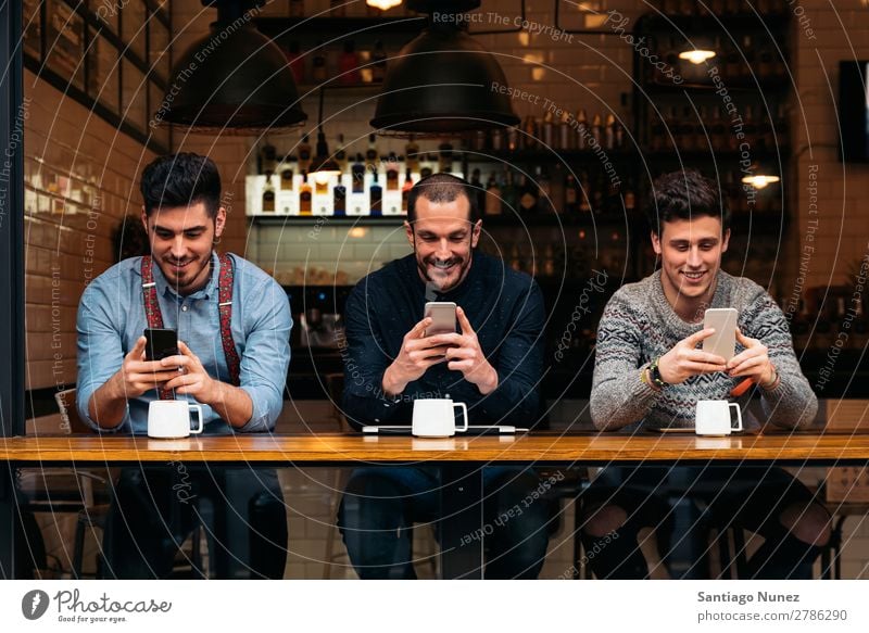 Freunde, die Handy und Laptop benutzen. Mann Kaffee Freundschaft Jugendliche Teamwork Menschengruppe Lifestyle PDA Mobile Mitteilung benutzend Text Computer