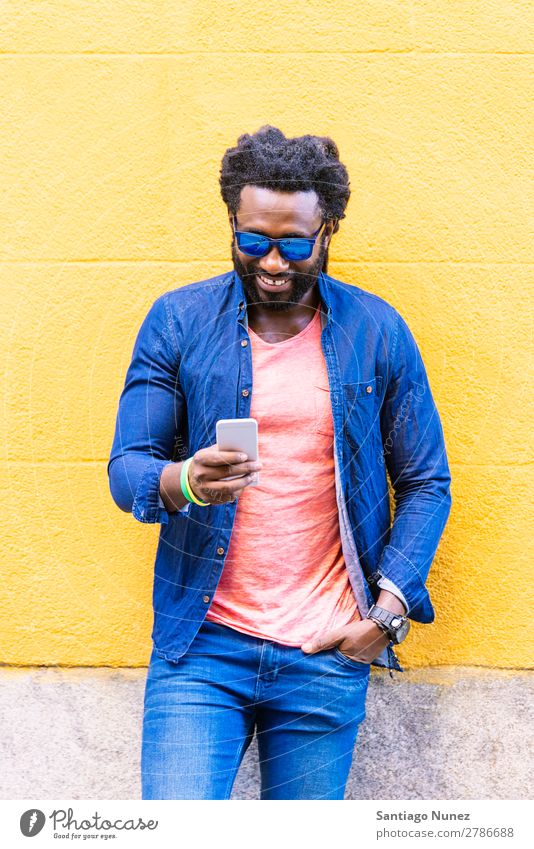 Afrikanischer junger Mann mit Handy auf der Straße. Lifestyle hören schwarz Amerikaner Stadt Porträt Telefon PDA Mobile Solarzelle Mitteilung Texten E-Mail