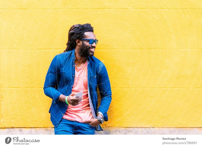 Afrikanischer junger Mann mit Handy auf der Straße. Lifestyle hören schwarz Amerikaner Stadt Porträt Telefon PDA Mobile Solarzelle Mitteilung Texten E-Mail