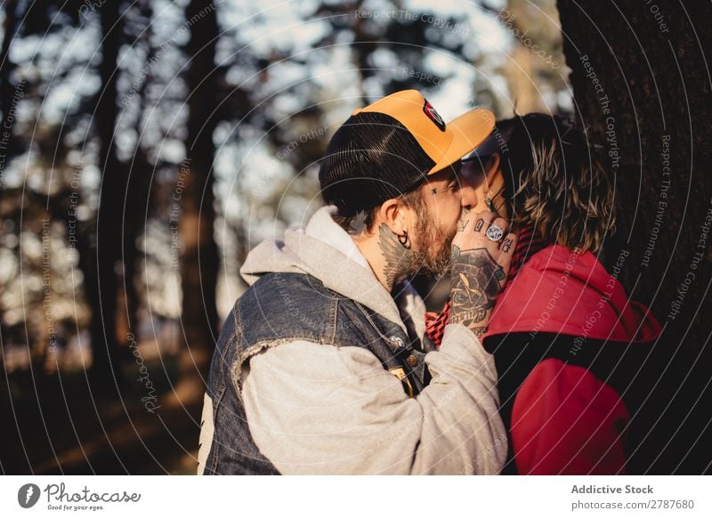 Ein glückliches Paar, das sich am Baum im Park umarmt und küsst. Umarmen Glück umarmend Rücken Holz Wald Jugendliche heiter bärtig Mann Frau Freude Schickimicki