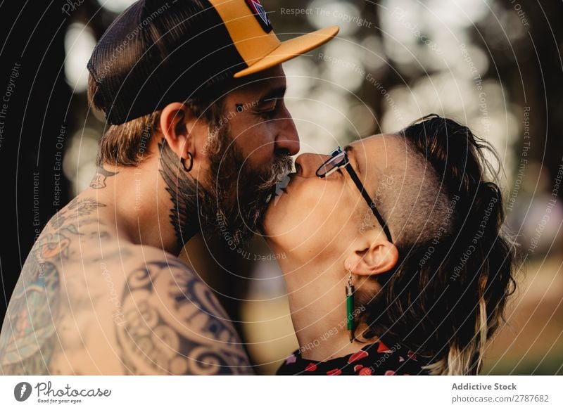 Junger Mann mit Tattoos umarmt die Dame im Wald. Paar Umarmen Schnappschuss Park ohne Hemd Typ Jugendliche Schickimicki umarmend Frau romantisch Kunst