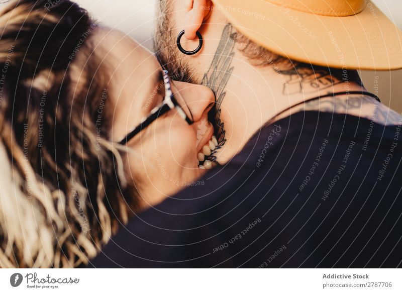 Junge Dame beißt Kerl in Tattoos beißen Paar beißend Hals Brille Ohrringe Schnappschuss Typ Jugendliche Schickimicki Mann Frau umarmend romantisch Umarmen Kunst
