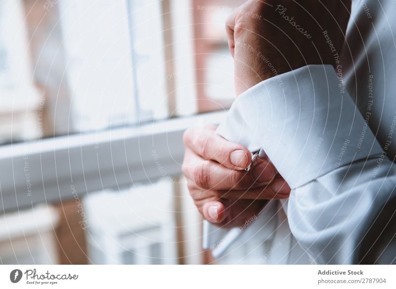 Mann knöpft Hemdärmel zu Hülse zuknöpfend Hand weiß Fenster Bekleidung Mode Design Textil anhaben Stil elegant Baumwolle lässig Knöpfe Stoff Sauberkeit formell