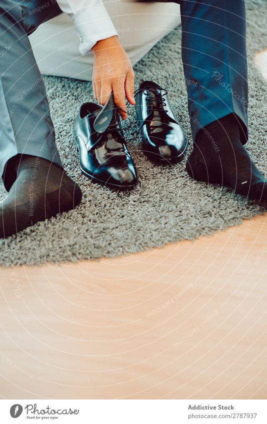 Mann in eleganten Stiefeln anhaben Teppich schwarz Hose sitzen Mode Leder Stil Fuß Design Blick Schuhe klassisch paarweise Konsistenz Unterlage formell Typ
