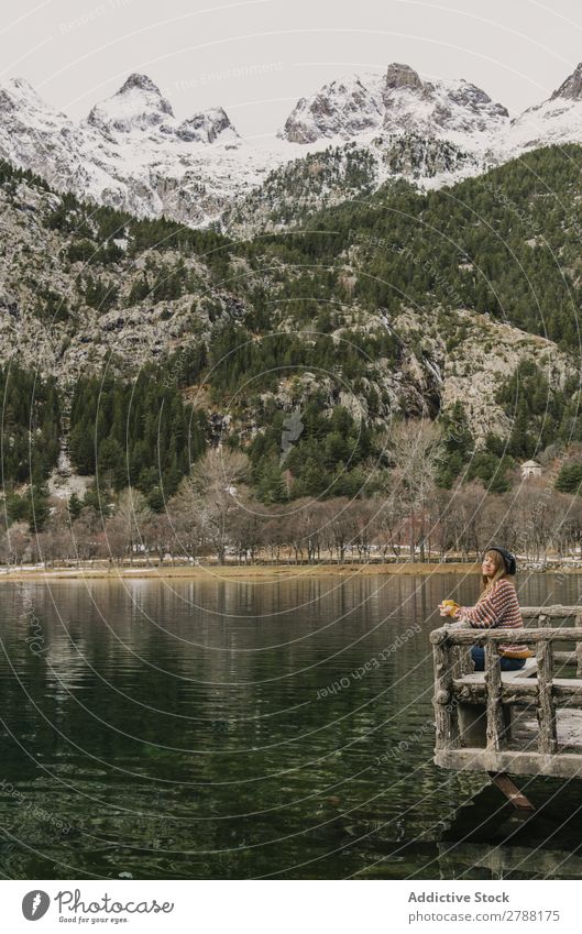 Frau auf Sitz in der Nähe des wunderschönen Sees zwischen Hügeln im Schnee und bewölktem Himmel. Pyrenäen wunderbar Wasser Oberfläche Berge u. Gebirge Wolken