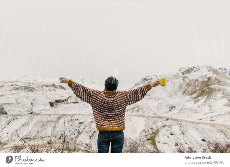 Junge Frau mit Kelch und Händen an den Seiten zwischen den Bergen Berge u. Gebirge Tasse Pyrenäen Hand Dame Pullover Hut Hügel Becher Schnee wunderbar
