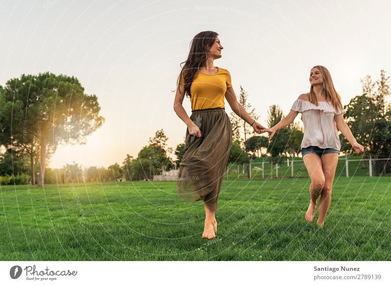 Schöne Frauen lächeln und Spaß haben und laufen. Picknick Freundschaft Jugendliche rennen Hand Spielen Park Glück Sommer Mensch Freude Erwachsene Mädchen hübsch