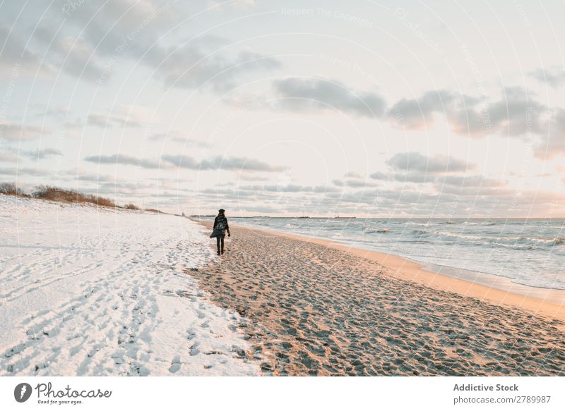 Frau, die an der Schneeküste am Meer spazieren geht. Küste laufen Litauen Klappeda Sand Wasser Mantel Hut Rucksack Natur Winter kalt Frost weiß Lifestyle Dame