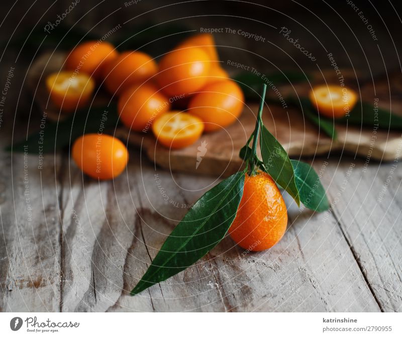 Kumquat-Früchte auf Holzuntergrund Frucht Dessert Ernährung Vegetarische Ernährung Diät exotisch Menschengruppe Blatt frisch natürlich saftig gelb grau Farbe