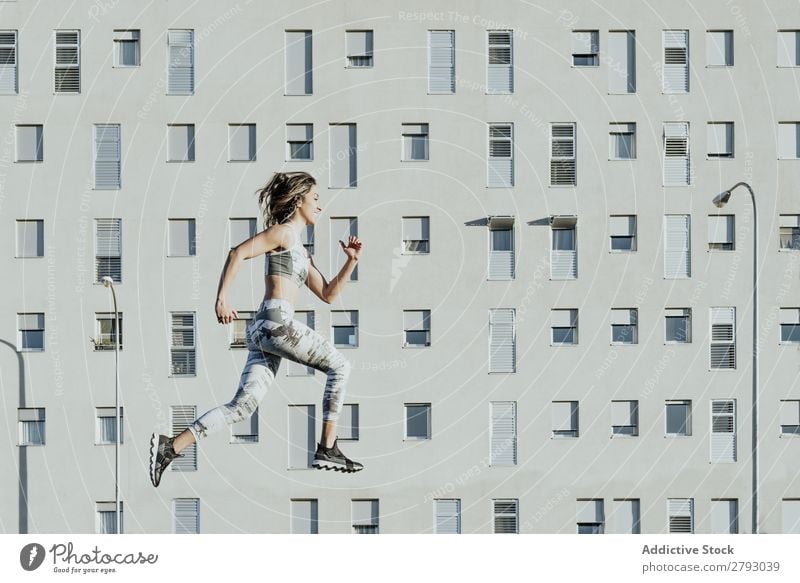 Frau in Sportbekleidung springend in der Nähe von Gebäuden sportlich Sonnenstrahlen Wetter dünn Dame schwebend fliegen Fitness Jugendliche Training üben Aktion