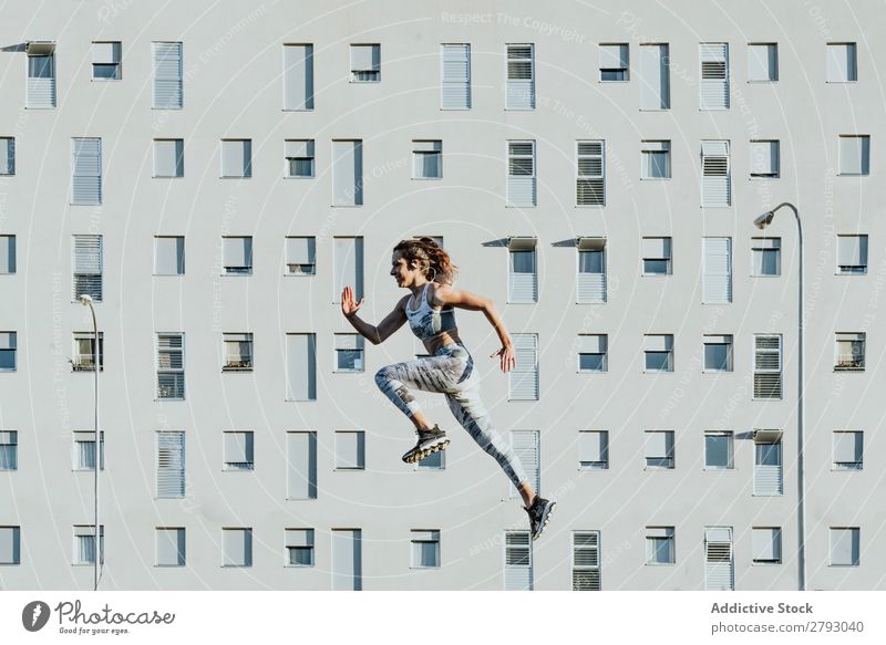 Frau in Sportbekleidung springend in der Nähe von Gebäuden sportlich Sonnenstrahlen Wetter dünn Dame schwebend fliegen Fitness Jugendliche Training üben Aktion