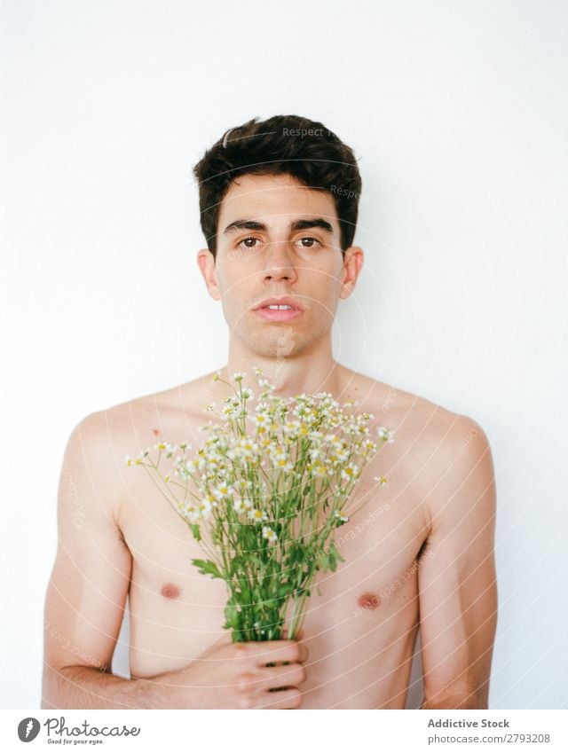 Junger Mann mit einem Blumenstrauß in den Händen. Mund Haufen Typ frisch Jugendliche brünett weiß ohne Hemd Überraschung Geschenk romantisch Gänseblümchen