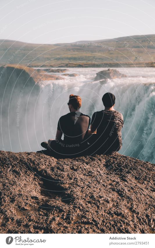 Anonyme Männer beim Betrachten des Wasserfalls Mann Klippe bewundernd Aussicht Natur Landschaft Arktis sitzen Zusammensein Ferien & Urlaub & Reisen Tourismus