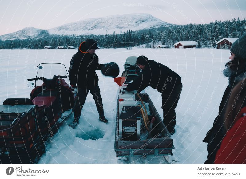 Junge Männer beim Beladen von Schneemobilen Mann Motorschlitten Beladung Landschaft Jugendliche Arktis Fahrzeug Zahnrad Ferien & Urlaub & Reisen Zusammensein
