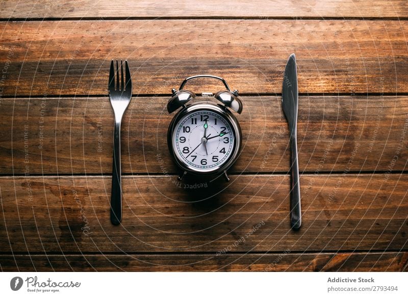 Besteck in der Nähe des Weckers Tisch Entwurf Diät Gabel Messer Zeit Mahlzeit Minutenzeiger Stundenzeiger Mittagessen Abendessen Frühstück mechanisch Metall