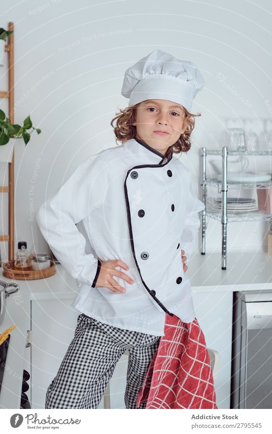 Junge mit Kochmütze in der Küche Möhre Küchenchef Kind Gemüse Hut frisch zeigen Hand Hüfte kochen & garen modern lustig heimwärts Licht vorbereitend