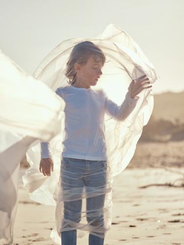 Kind in Plastik verstrickt an der Flussküste Junge Kunststoff Textil winkend Küste Seite Wind Sand Wasser Berge u. Gebirge Landschaft Strand Hilfsbereitschaft