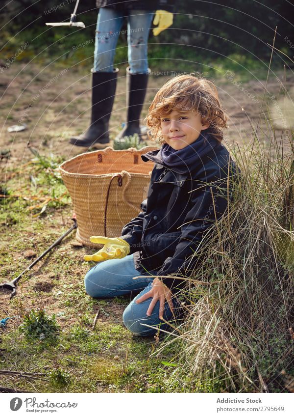 Junge mit Müllhaufen in den Händen in der Nähe des Korbes Müllbehälter abholend Boden Kind Park Abfall Kommissionierer Container Aufräumen Umwelt Kunststoff