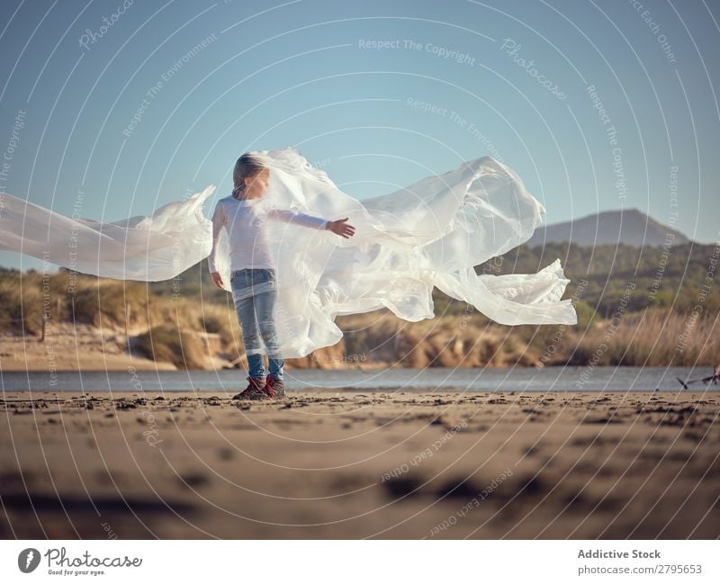 Kind in Plastik verstrickt an der Flussküste Junge Kunststoff Textil winkend Küste Seite Wind Sand Wasser Berge u. Gebirge Landschaft Strand Hilfsbereitschaft