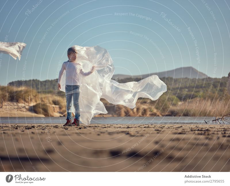 Mädchen in Plastik verstrickt an der Flussküste Kunststoff Textil winkend Küste Seite Wind Sand Wasser Berge u. Gebirge Landschaft Strand Hilfsbereitschaft weiß