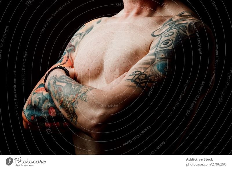Junger Mann ohne Hemd mit Tattoos Schickimicki Jugendliche Typ gekreuzte Hände Hand zeigen gutaussehend Kunst Coolness Studioaufnahme Haut Design Interesse