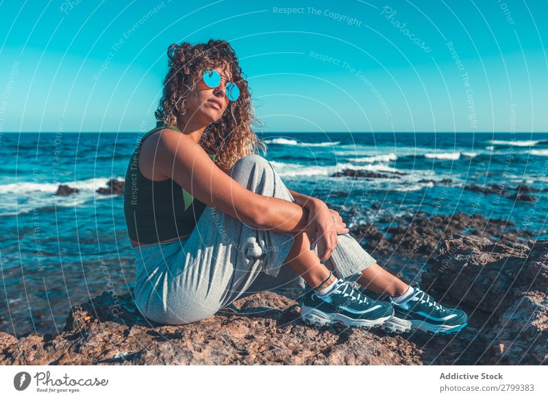 Stilvolle Frau am Meer sitzend Küste träumen Wegsehen umarmende Knie Lifestyle Freizeit & Hobby ruhen Erholung Wellen Wasser trendy lässig Sonnenbrille Himmel