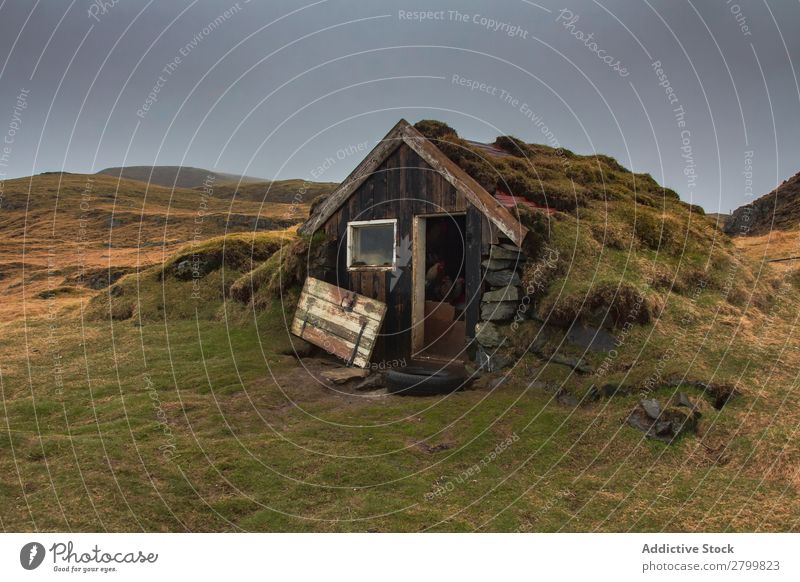 Beschädigte Hütte auf dem Land schäbig Landschaft Island kaputt Tür Moos Gras Außenseite Schaden Hauseingang grau Himmel matt verwittert Bruchbude alt Gebäude