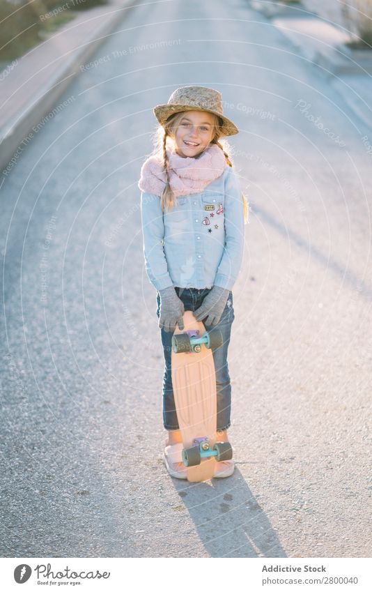 Stylisches Mädchen mit Skateboard auf der Straße blond Vorstadt Stil stehen Sonnenstrahlen Tag Kind trendy lässig Lifestyle Freizeit & Hobby harmonisch Idylle