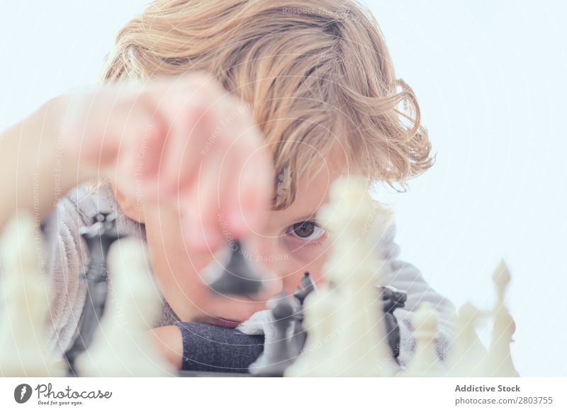 Junge mit Figur auf dem Schachbrett blond Tisch Spielen klug zeigen Kind weiß Gardine Freude Freizeit & Hobby Verstand Strategie Konzentration Bildung Mann
