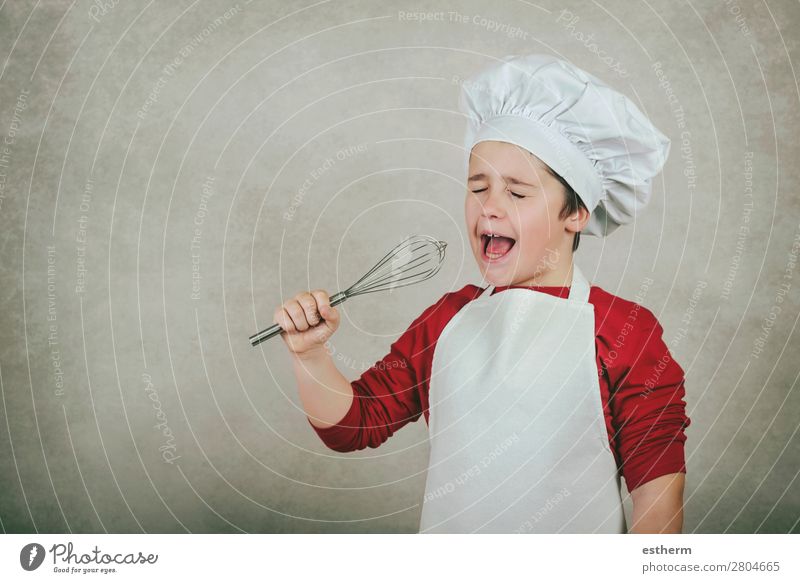 lustiger Junge mit Kochmütze, der den Schneebesen in einer Hand hält. Ernährung Abendessen Diät Lifestyle Musik Restaurant Kind Beruf Gastronomie Business