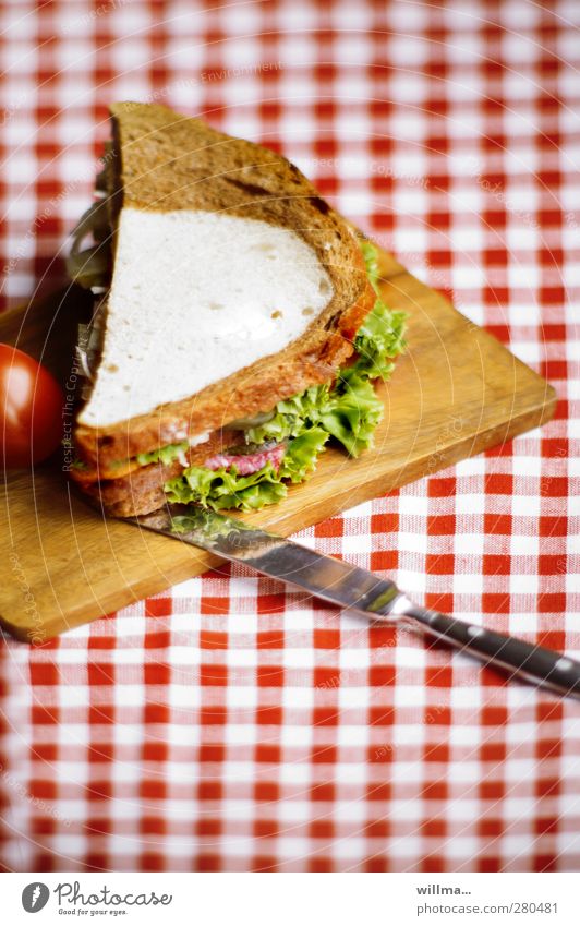 Sandwich aus Schwarzbrot und Weißbrot, belegt mit Salami und Salat Tomate Salatbeilage Belegtes Brot Messer Schneidebrett lecker Tischdecke rotkariert rot-weiß