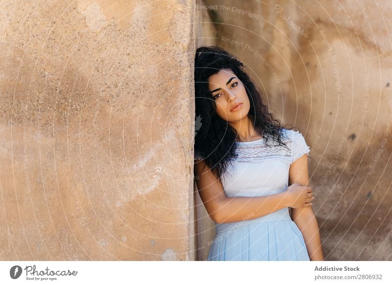 Schöne ethnische Frau in der Nähe einer schäbigen Mauer. Marokkaner Wand urwüchsig elegant anlehnen Außenseite Gebäude Jugendliche Model dünn dreckig genießen