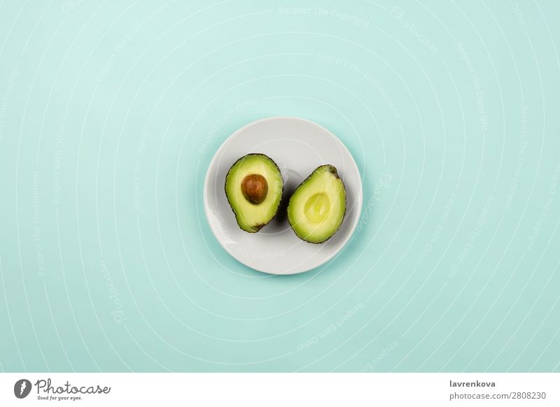 Avocado auf weißem Teller auf pastellfarbenem Hintergrund schneiden Scheibe natürlich roh frisch grün geschnitten reif organisch Ernährung