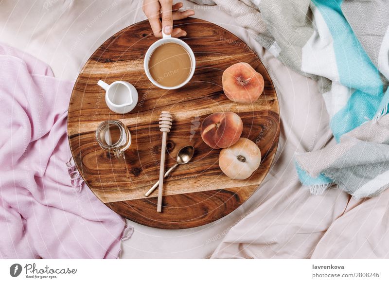 Gemütliches Flachbett aus Holztablett mit Tasse Kaffee, Pfirsichen, Kaffeesahne und Sahne. Becher Flachlegung flache Verlegung Schlafzimmer Frühstück Espresso