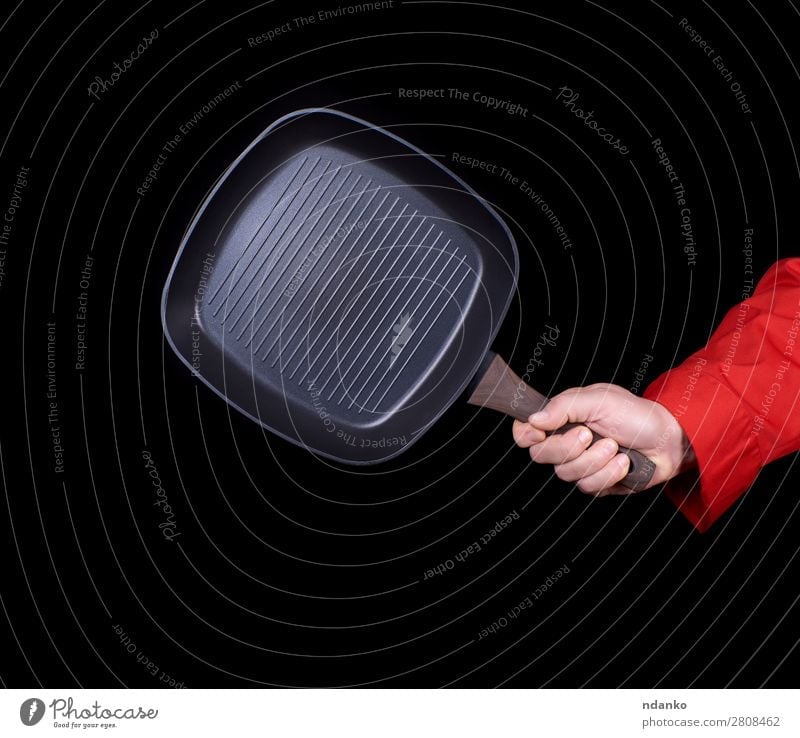 Hand hält eine schwarze, leere, quadratische Grillpfanne. Pfanne Küche Restaurant Beruf Koch Werkzeug Mann Erwachsene Metall Stahl festhalten neu rot Gußeisen