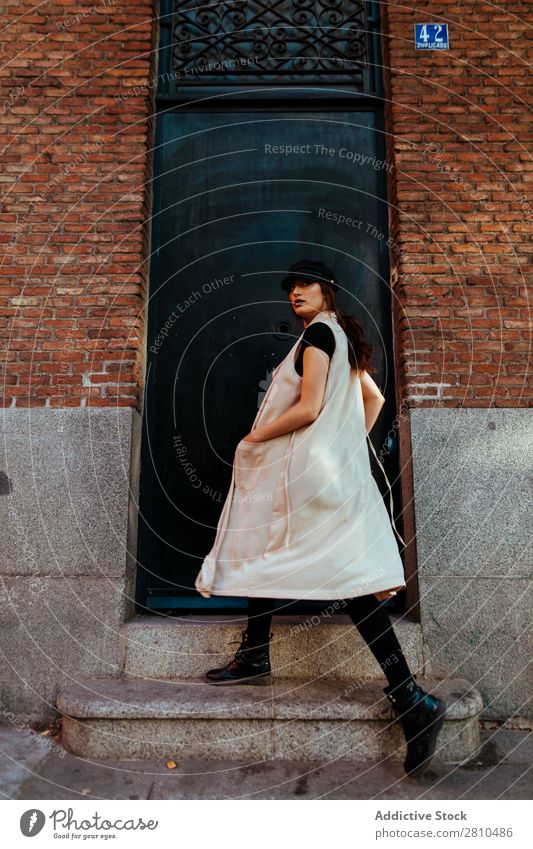 Stilvolle Frau, die zum Haus geht. Jugendliche Straße schön Mütze Veranda Backstein laufen Großstadt Mode hübsch attraktiv Model Mensch Beautyfotografie Porträt